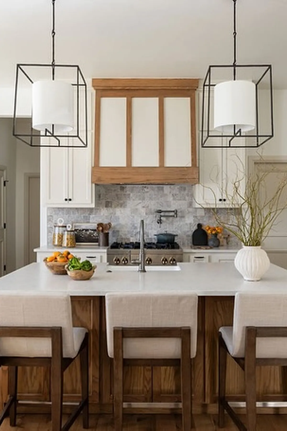 Geometric frame pendant lights over a kitchen island with white and wood cabinetry.