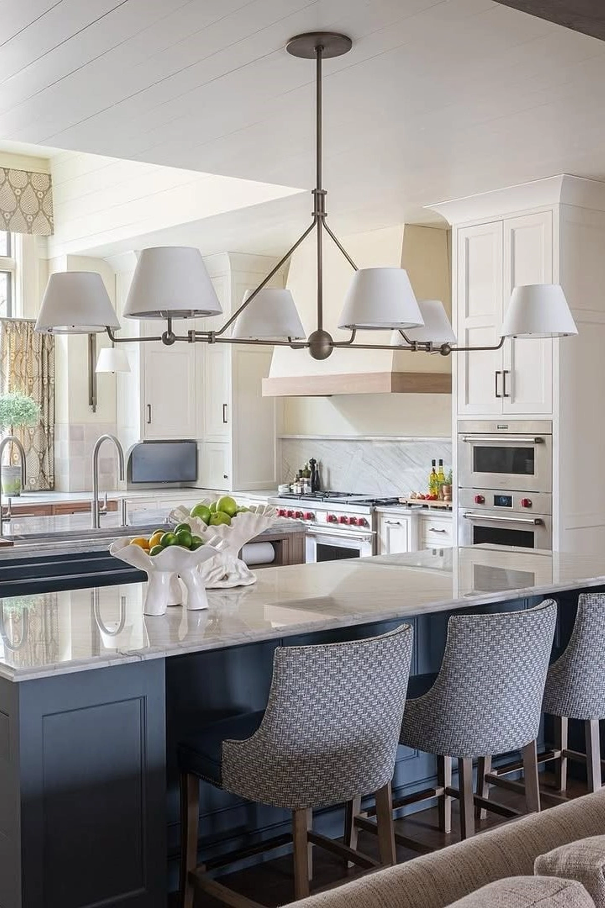 Dual sconce-style lights with white shades over a blue kitchen island with seating.