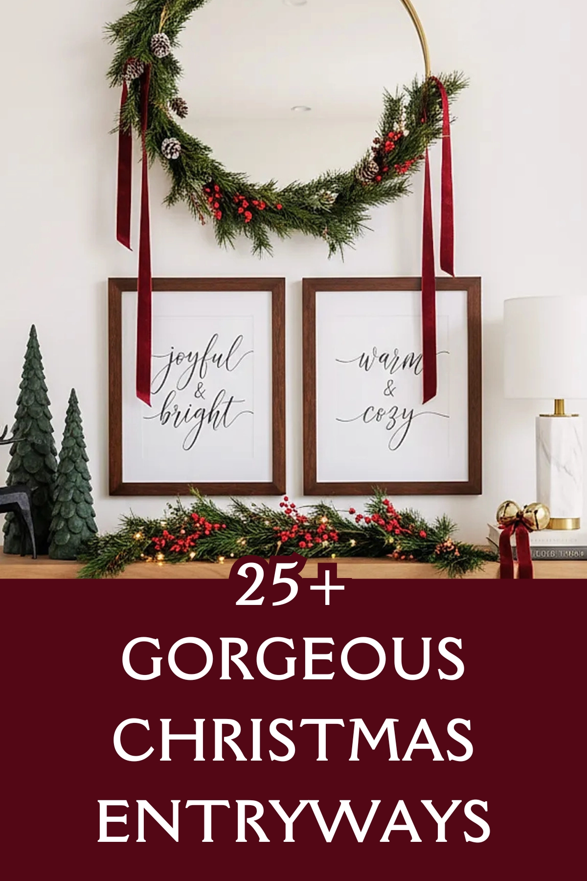 Christmas entryway with large round brass mirror decorated with pine and berry wreath tied with long red velvet ribbons, console table with greenery garland, red berries, green Christmas tree figurines, black reindeer figurine, white lamp with gold base, burgundy banner with text '25+ Gorgeous Christmas Entryways'.