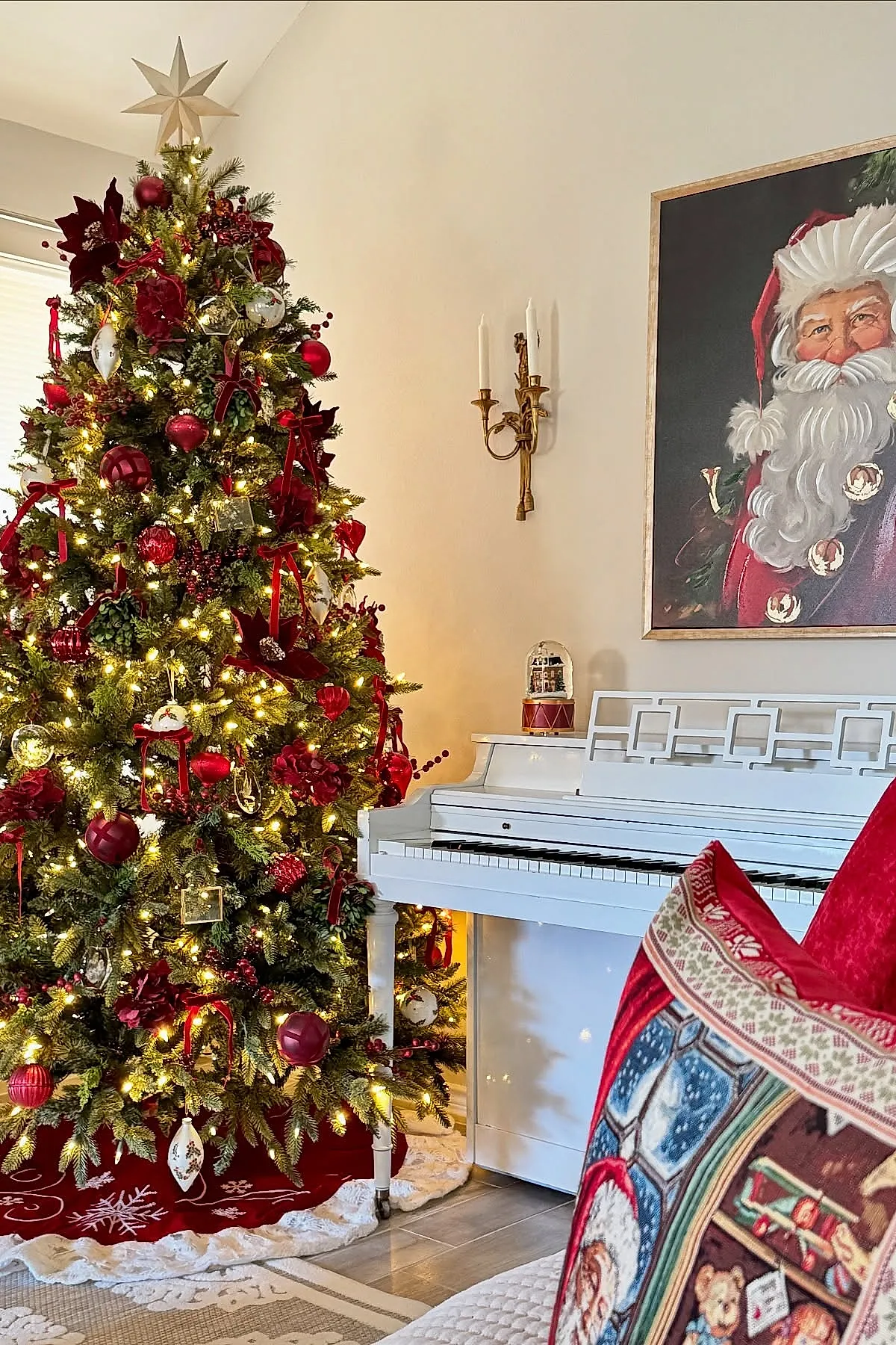 A traditional christmas tree decorated with deep red velvet flowers, red ribbons, vintage-style glass ball ornaments in red and gold tones, white string lights, topped with a large gold star.
