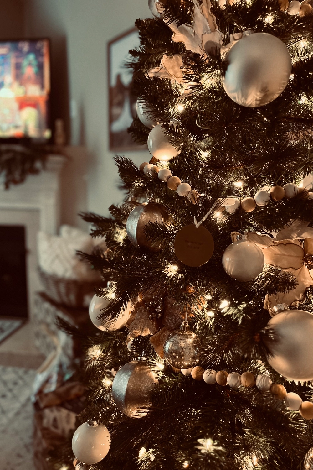traditional Christmas tree decorated with white and gold ornaments, wooden bead garland, and warm white lights in a cozy living room