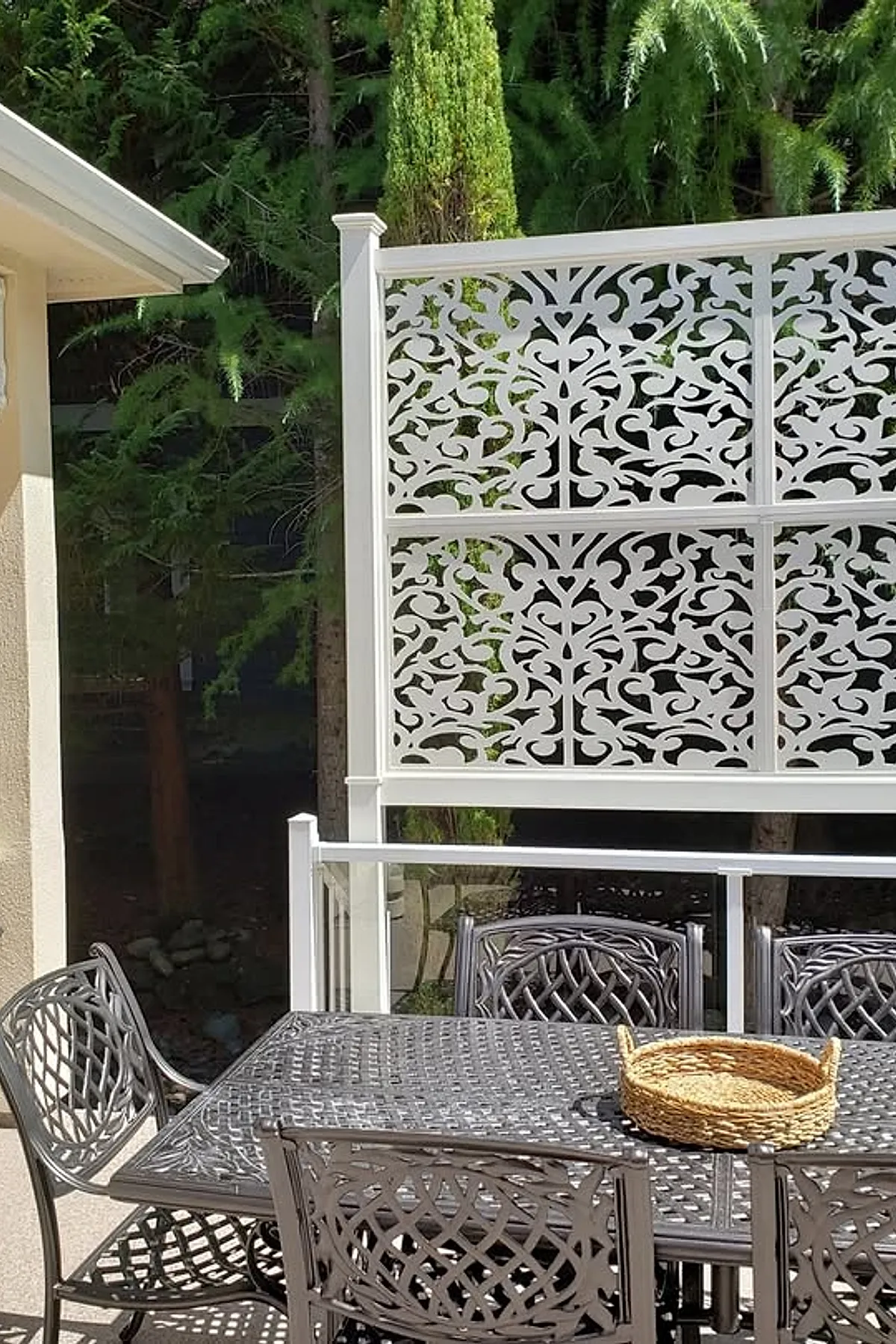 Decorative white lattice panels provide privacy on a patio with metal furniture.