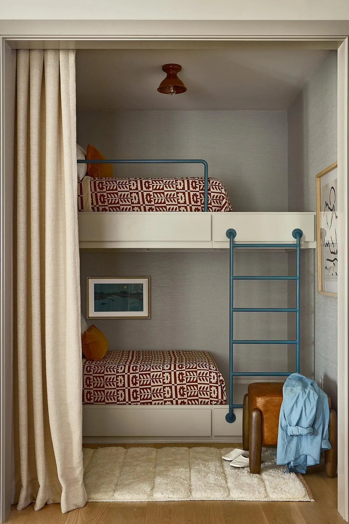 Built-in bunk beds with patterned bedding, blue ladder, and soft lighting create a modern, cozy sleeping nook.