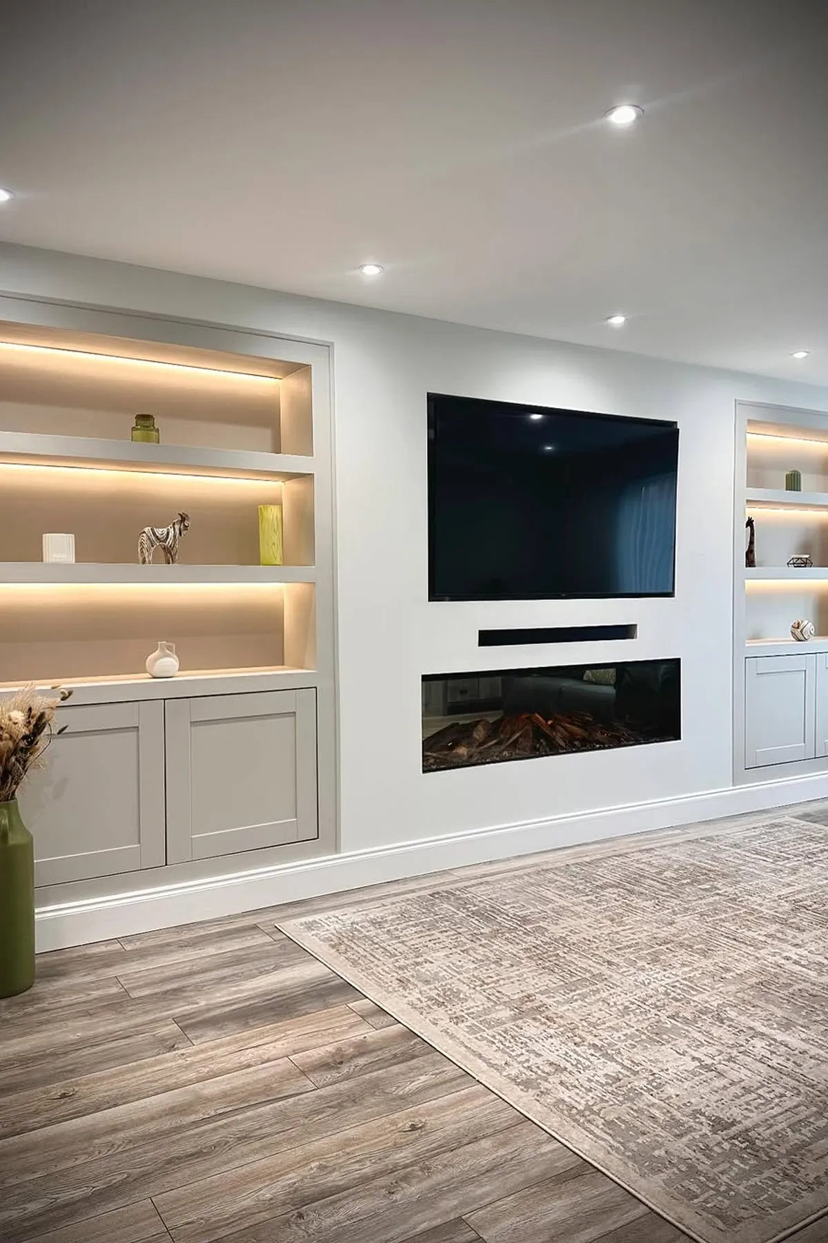 Modern living area featuring fireplace and tv surrounded by built in shelving and cabinets