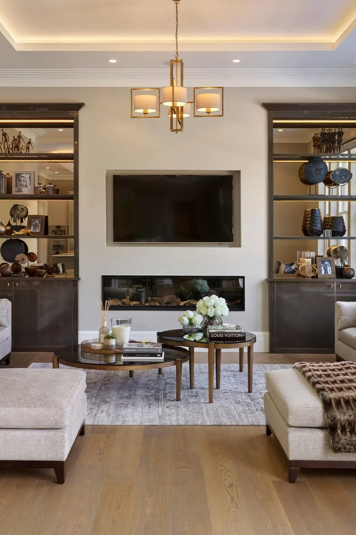 living room scene with modern fireplace and tv hung above surround by built in shelving