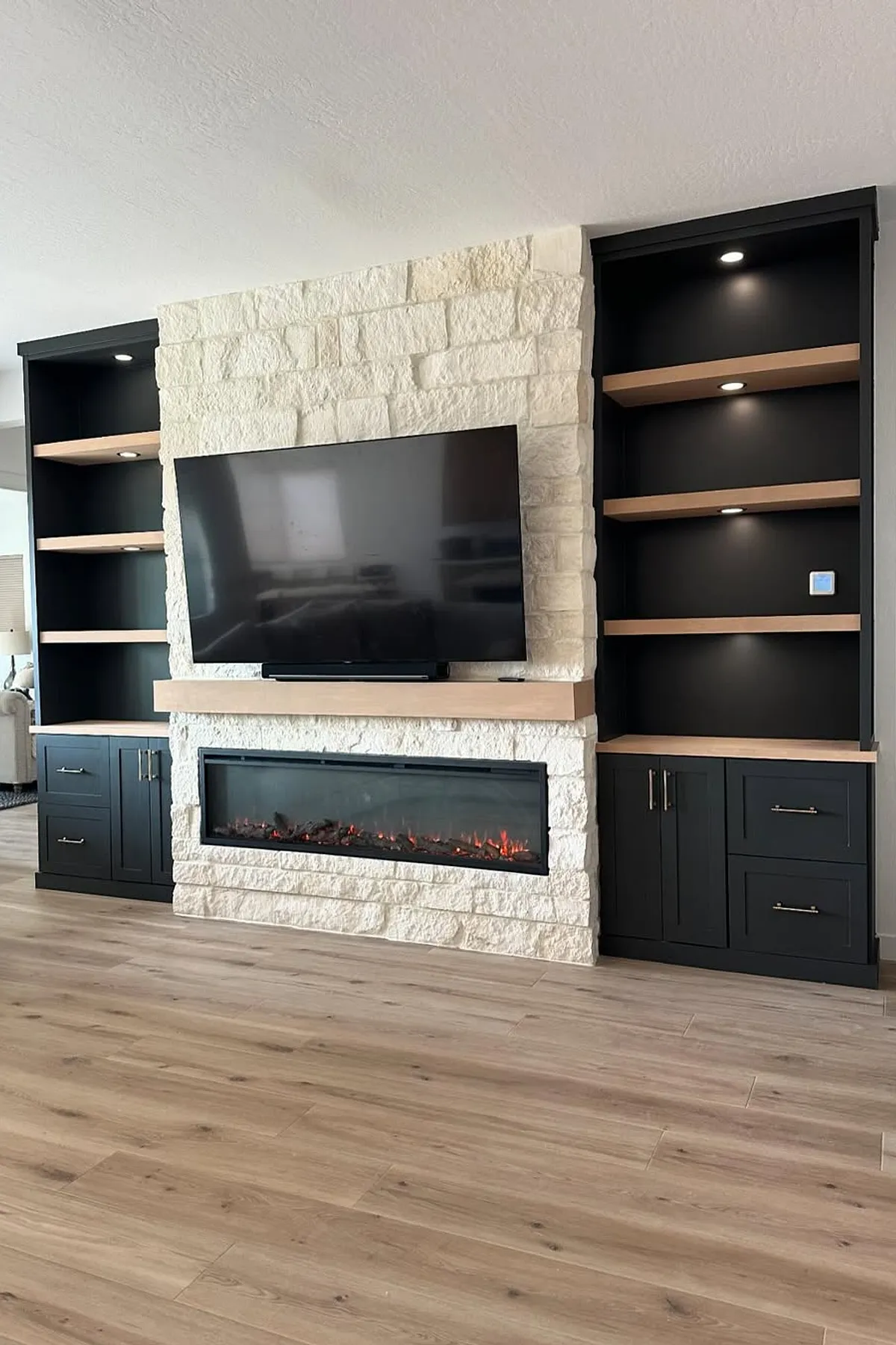 fireplace with tv above surrounded by dark built in shelving