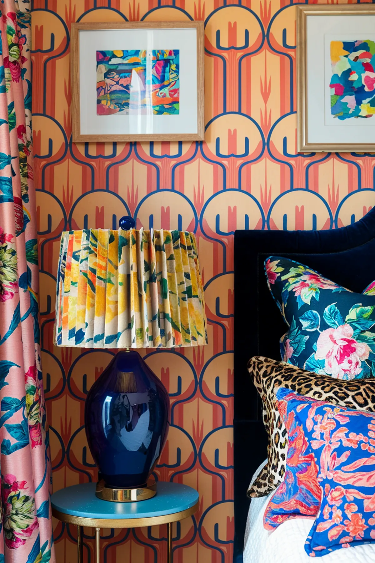 Eclectic bedroom with geometric wallpaper, floral curtains, and colorful pillows.