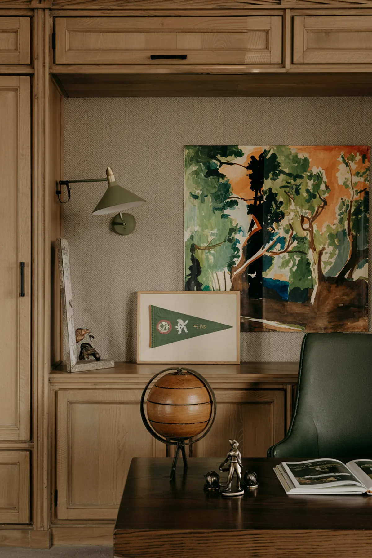 Home office with floral wallpaper, white desk, iMac computer, gold accent lighting, and vase of flowers.