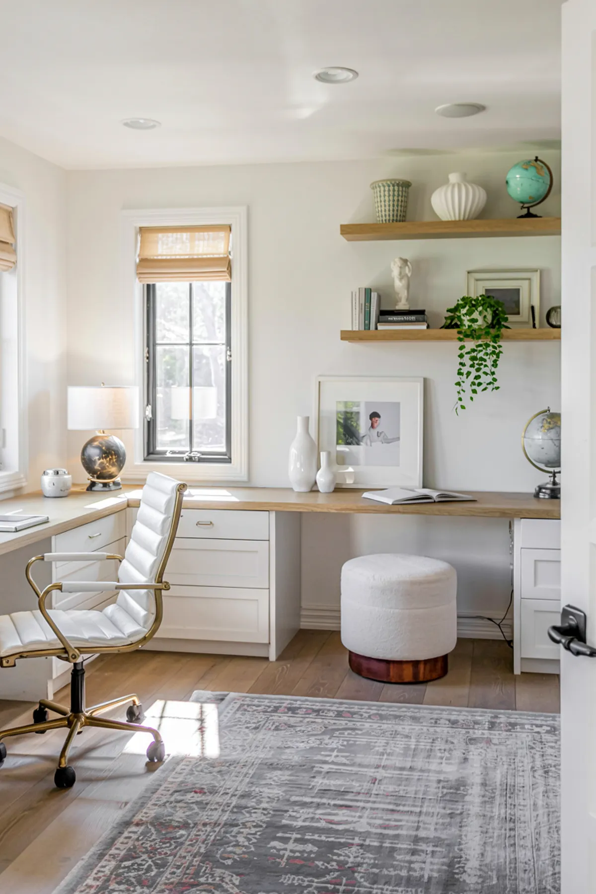 Home office with wooden shelves, colorful artwork, decorative globe, and stylish green chair.