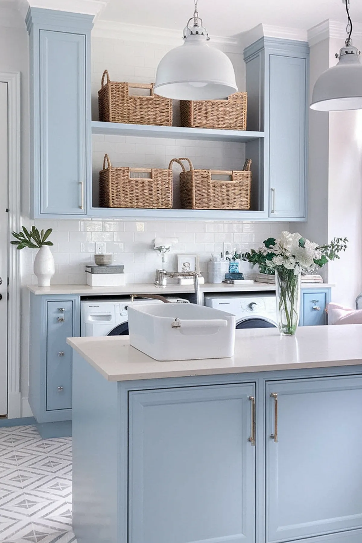A bright laundry room featuring light blue cabinets and woven baskets.