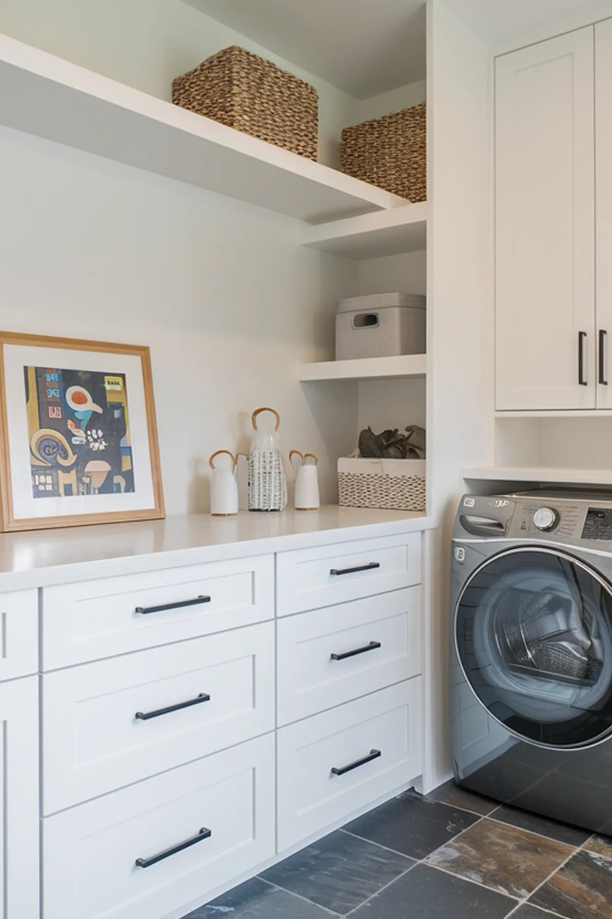 A sleek laundry room featuring white cabinets, black hardware, and stylish decor.