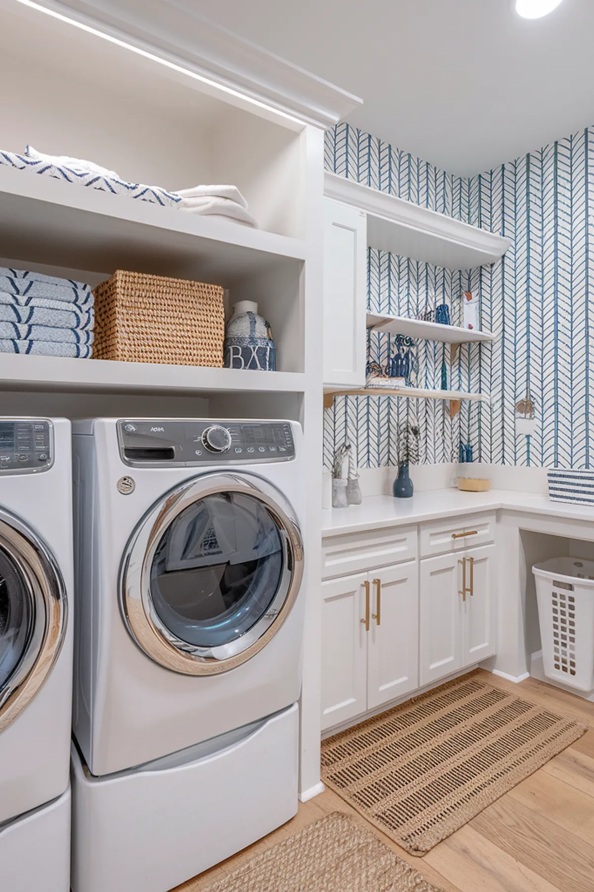 A coastal-inspired laundry room featuring blue patterned wallpaper and organized storage.