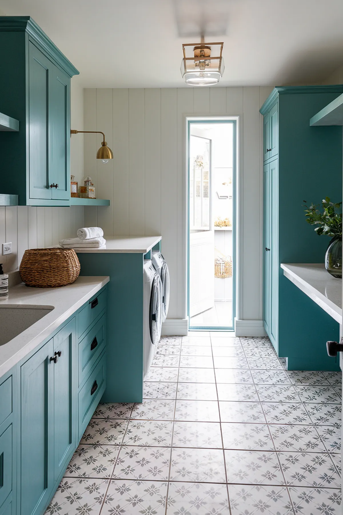 A vibrant laundry room featuring teal cabinets and patterned flooring.