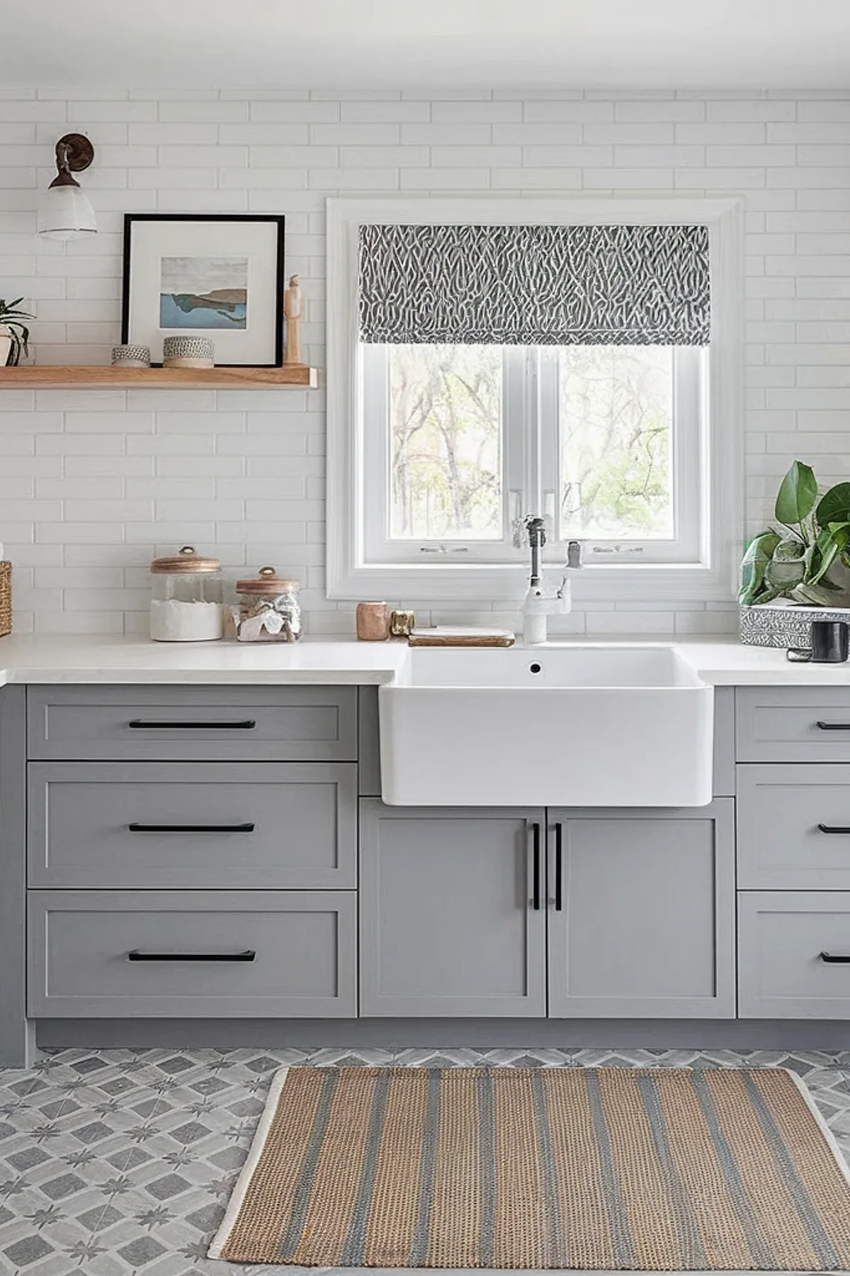 A modern laundry room featuring gray cabinets, a farmhouse sink, and patterned flooring.