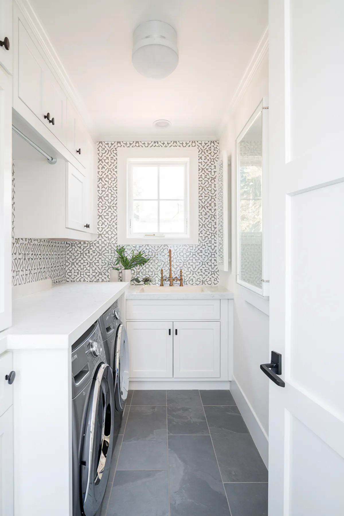 An elegant laundry room with a patterned tile backsplash and modern appliances.