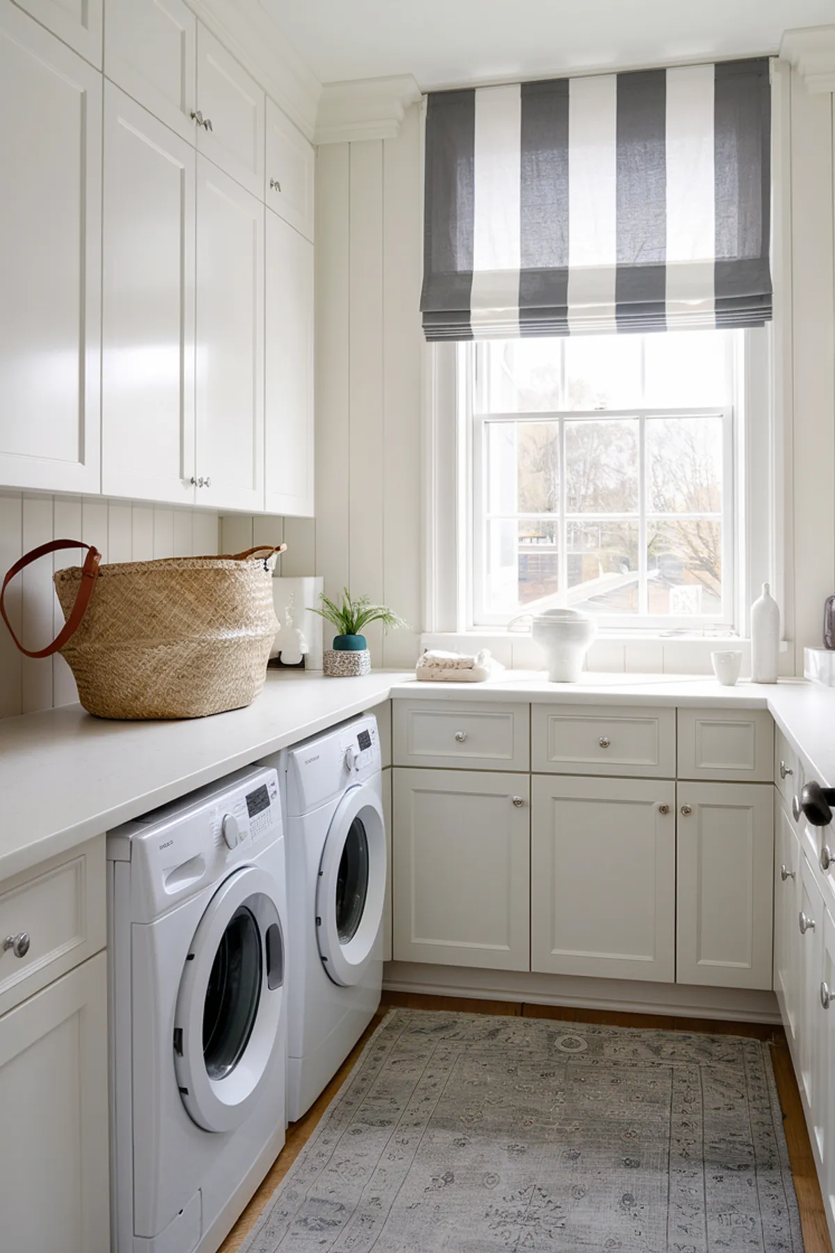A bright laundry room with white cabinets, striped curtains, and organized storage.