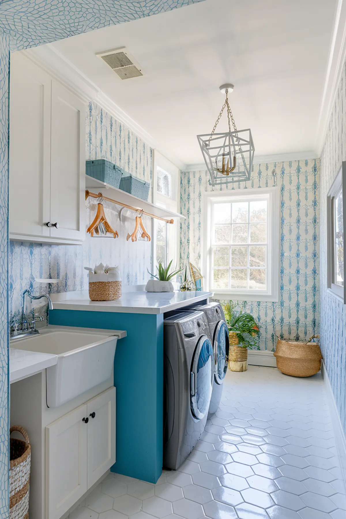 A coastal-inspired laundry room featuring blue wallpaper, hexagonal tiles, and modern appliances.