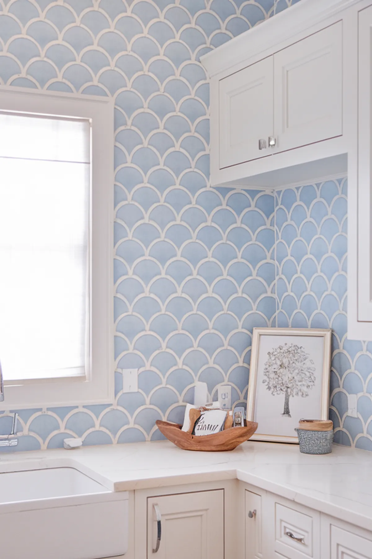A stylish laundry room with scalloped blue wallpaper and a farmhouse sink.