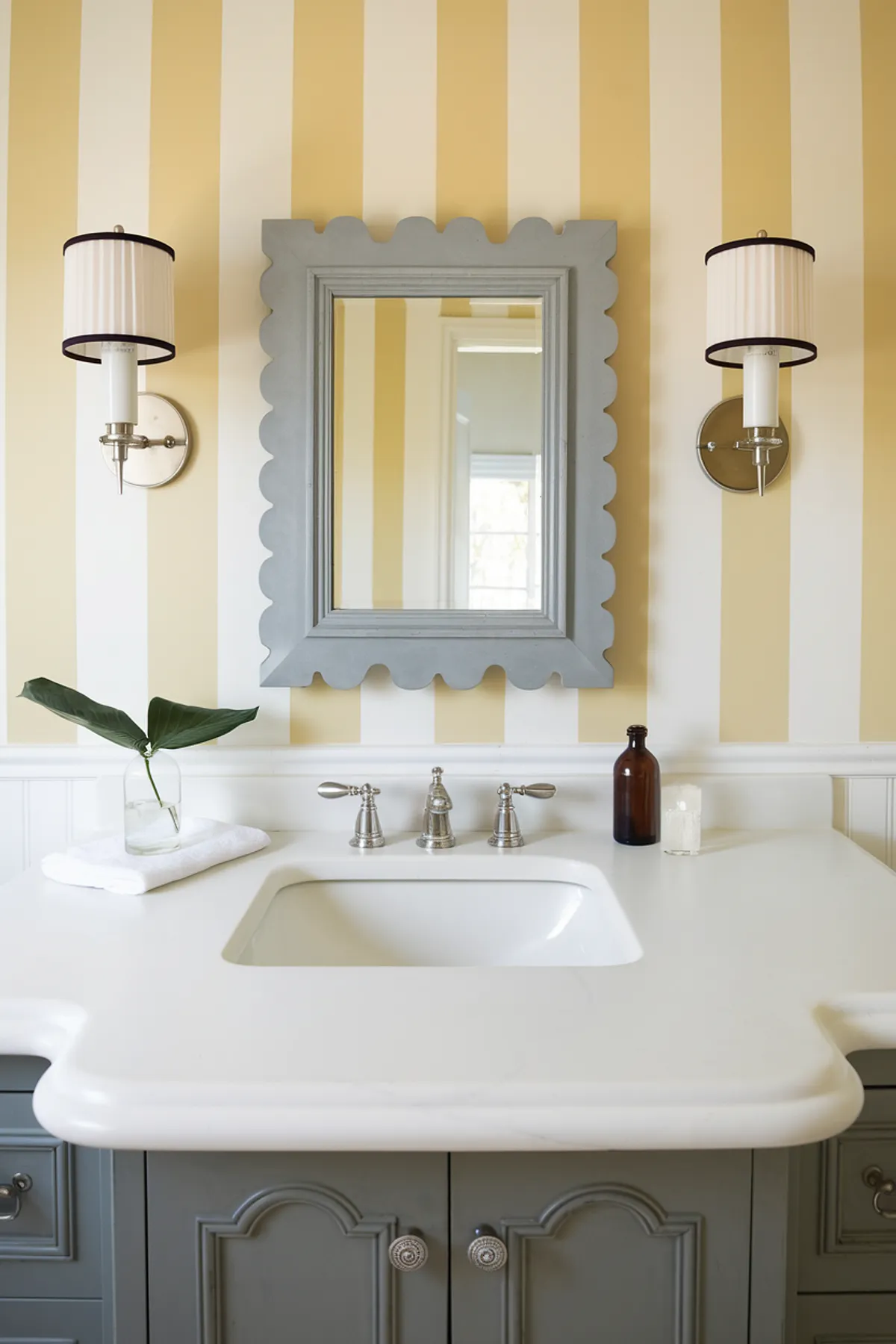 A bright bathroom featuring striped walls, a scalloped mirror, and stylish fixtures.