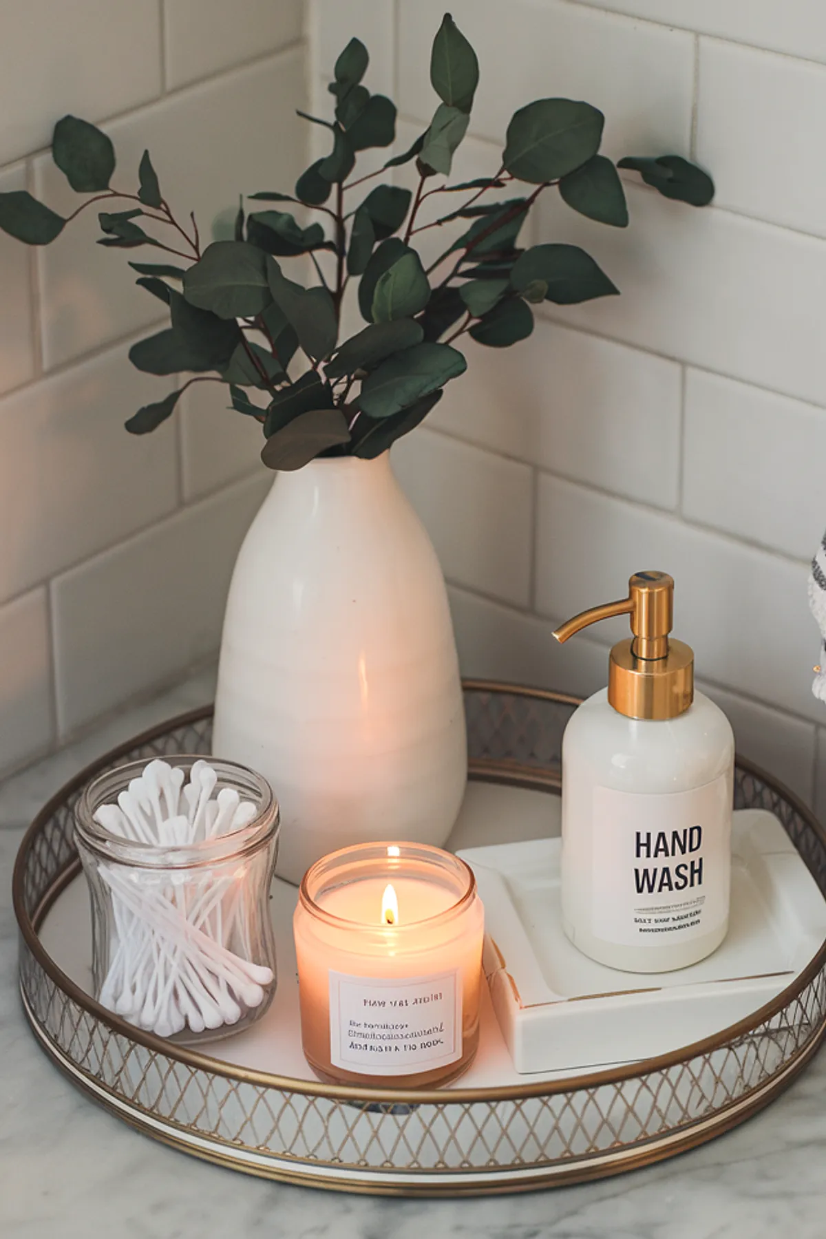 A beautifully styled bathroom tray with hand wash, candle, cotton swabs, and greenery.