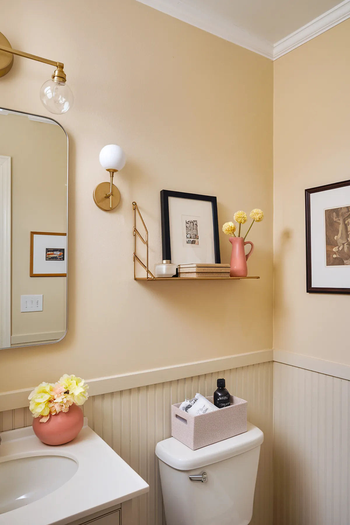 A stylish bathroom corner featuring peach walls, a mirror, and decorative accents.