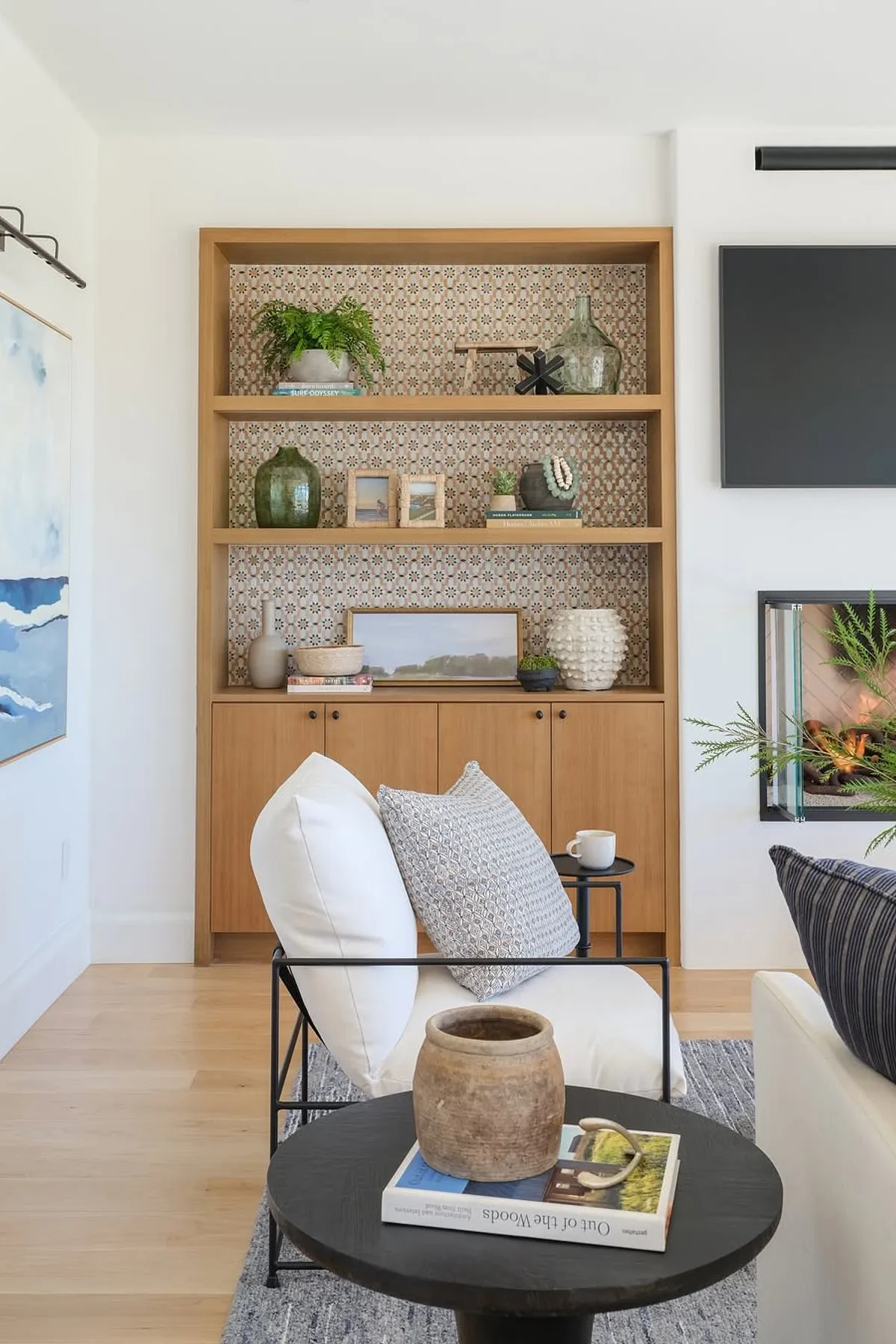 Modern shelf styling featuring glass vases, framed photos, and decorative objects in a living room.