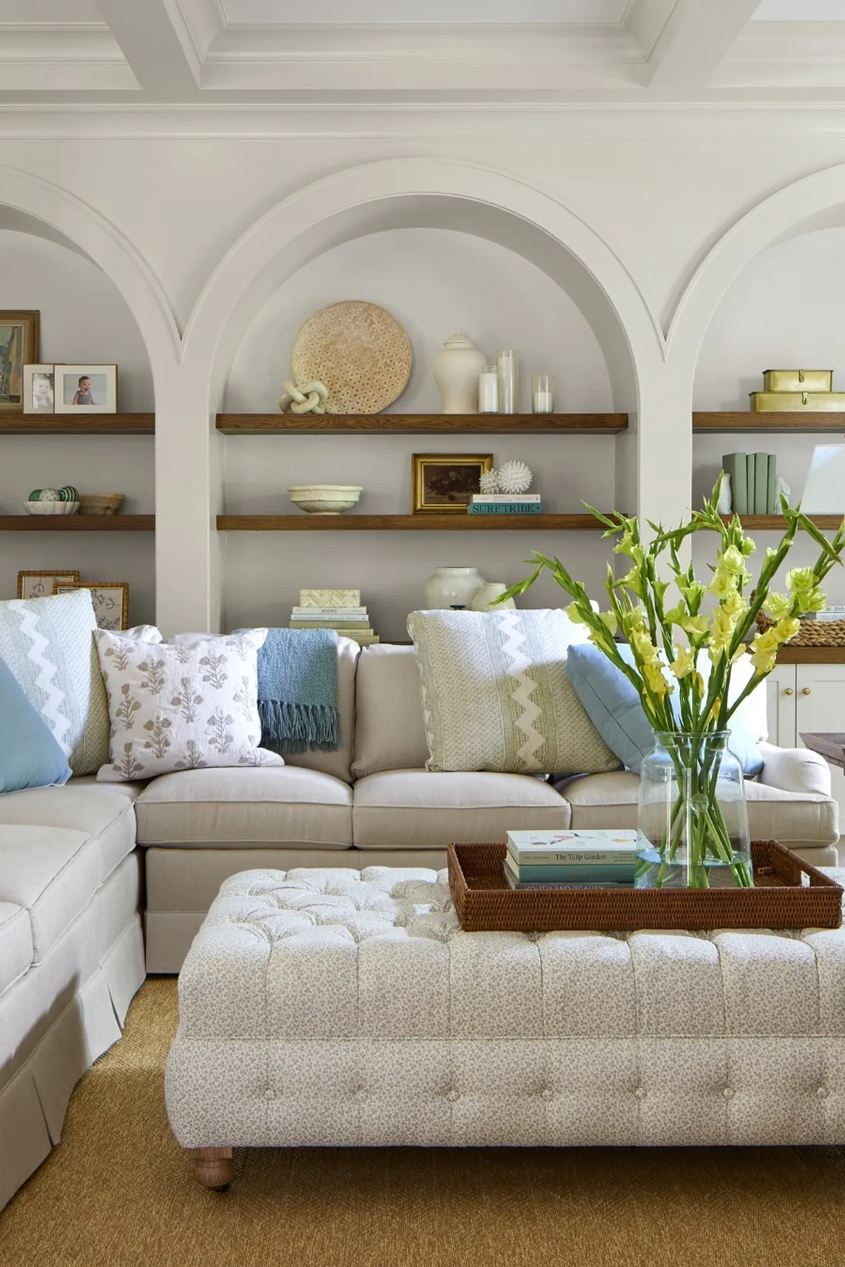 Living room featuring an L-shaped sofa, arch shelving with decorative items, and textured pillows.