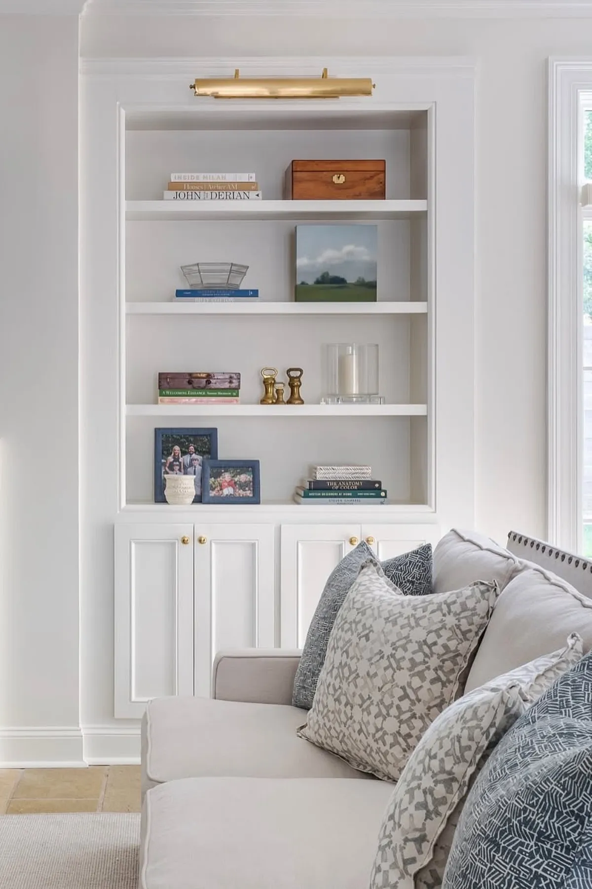 Modern shelf styling featuring neutral tones, books, decorative items, and framed photos in a living room.