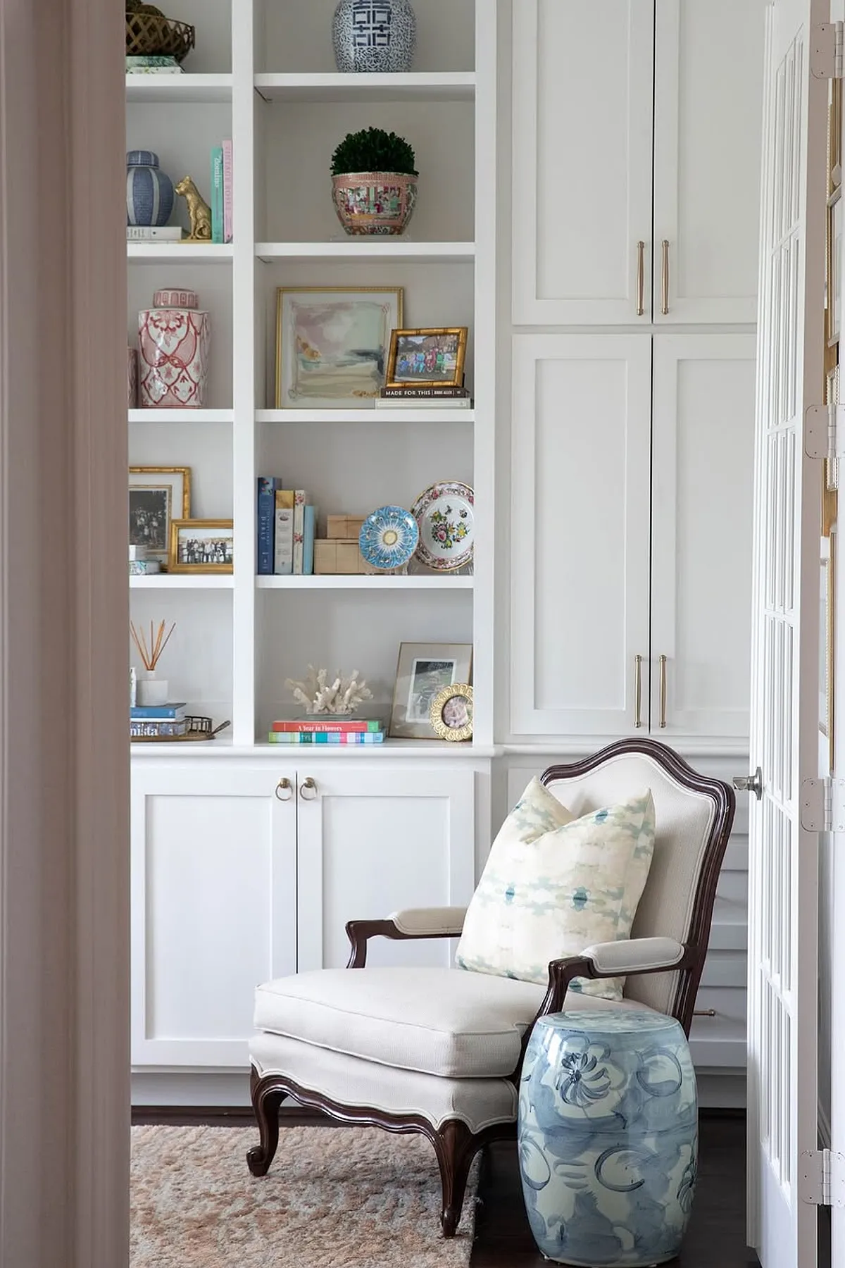 Stylish living room featuring white shelves, colorful decor items, an elegant armchair, and a decorative side table.
