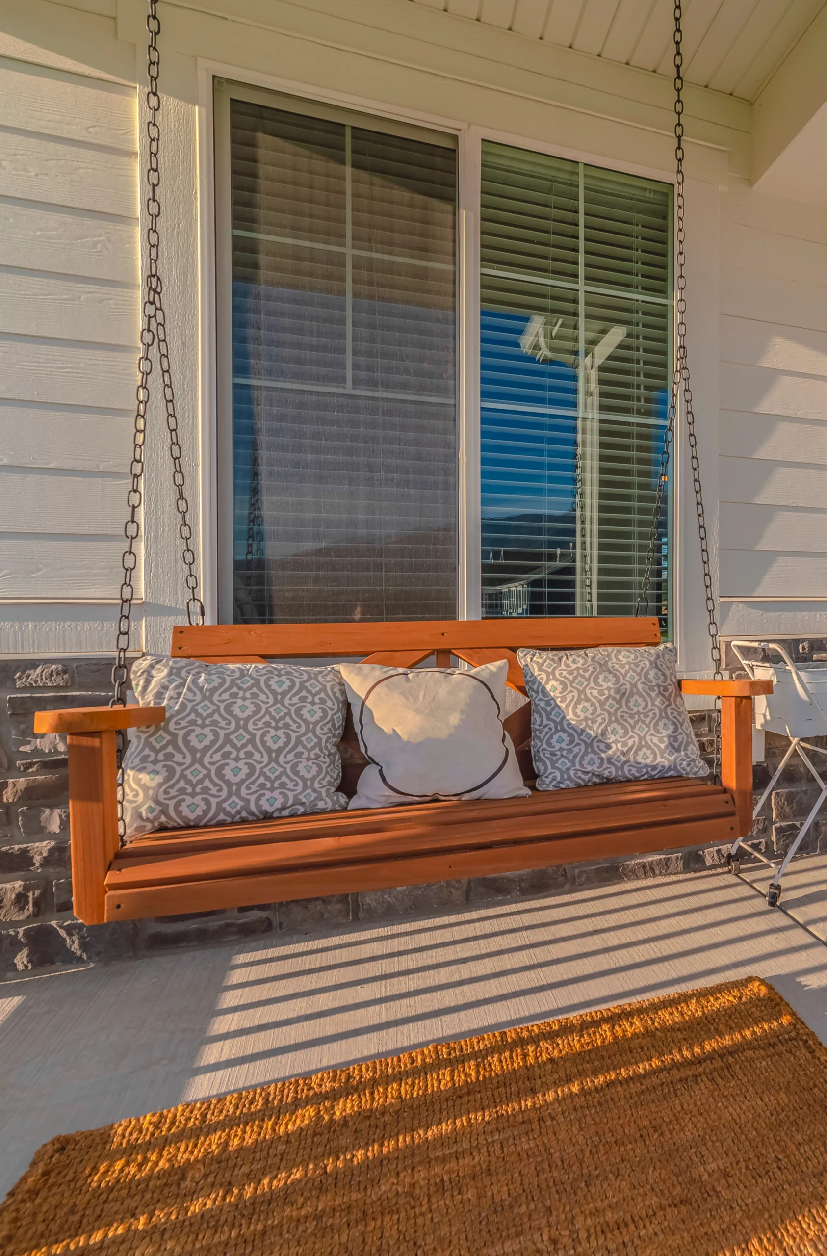 Wooden porch swing adorned with decorative pillows