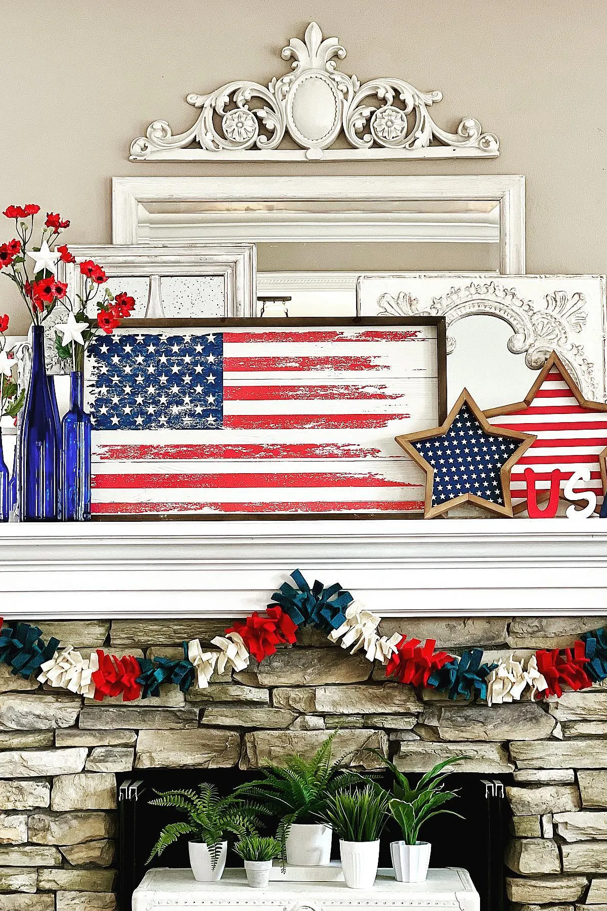 A 4th of July themed fireplace mantel featuring an American flag sign, blue vases, stars, and festive garland.