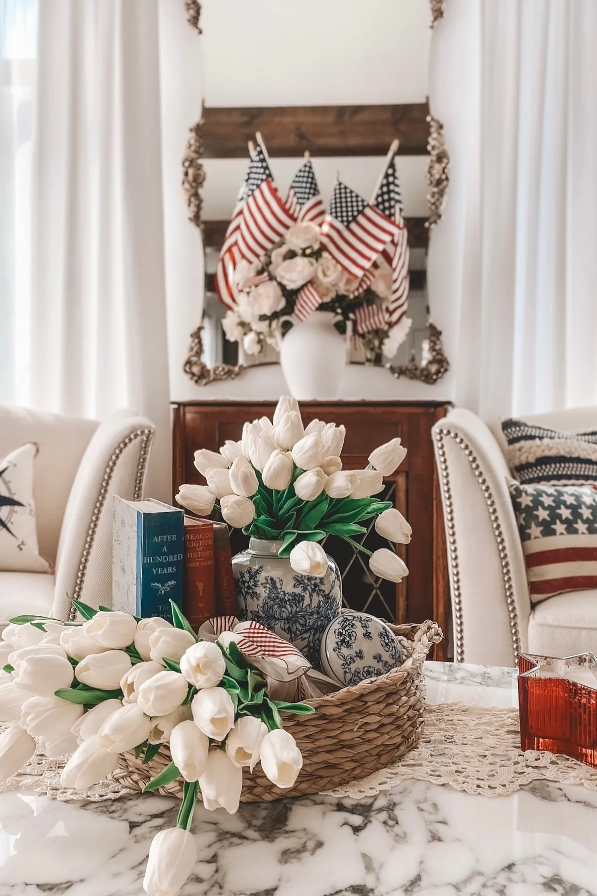 A cozy living room featuring white tulip arrangements, American flags, decorative books, and stylish textiles.