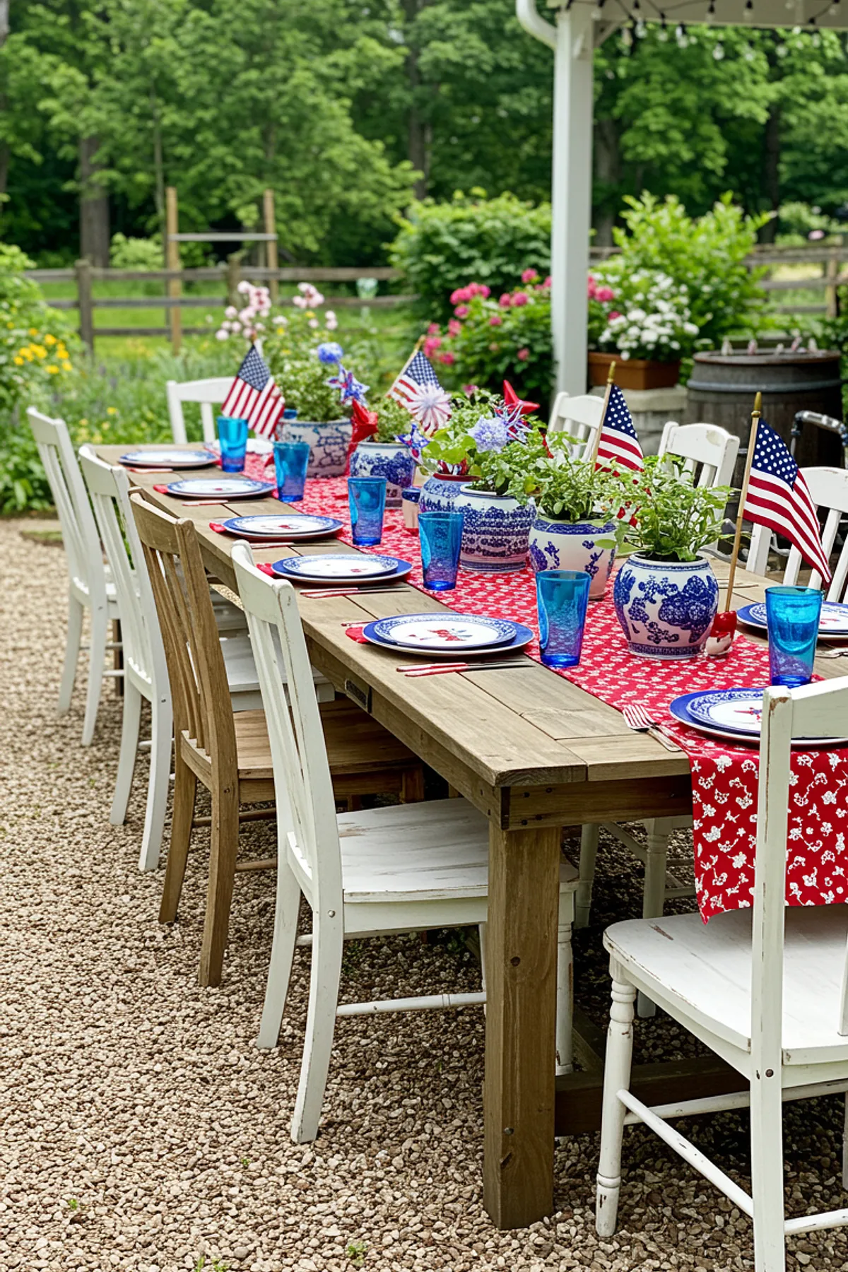 A festive outdoor dining table decorated with red table runner, blue glasses, white plates, and American flags.