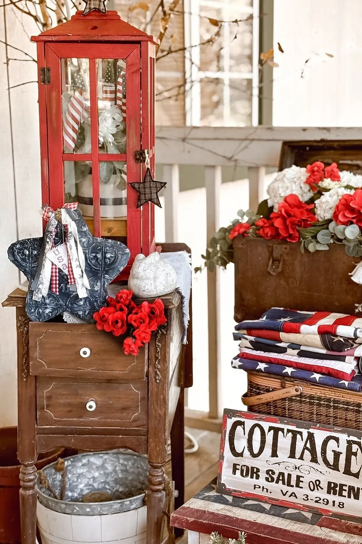 A cozy patio setup featuring a red lantern, star decor, flowers, vintage chest, and patriotic textiles.