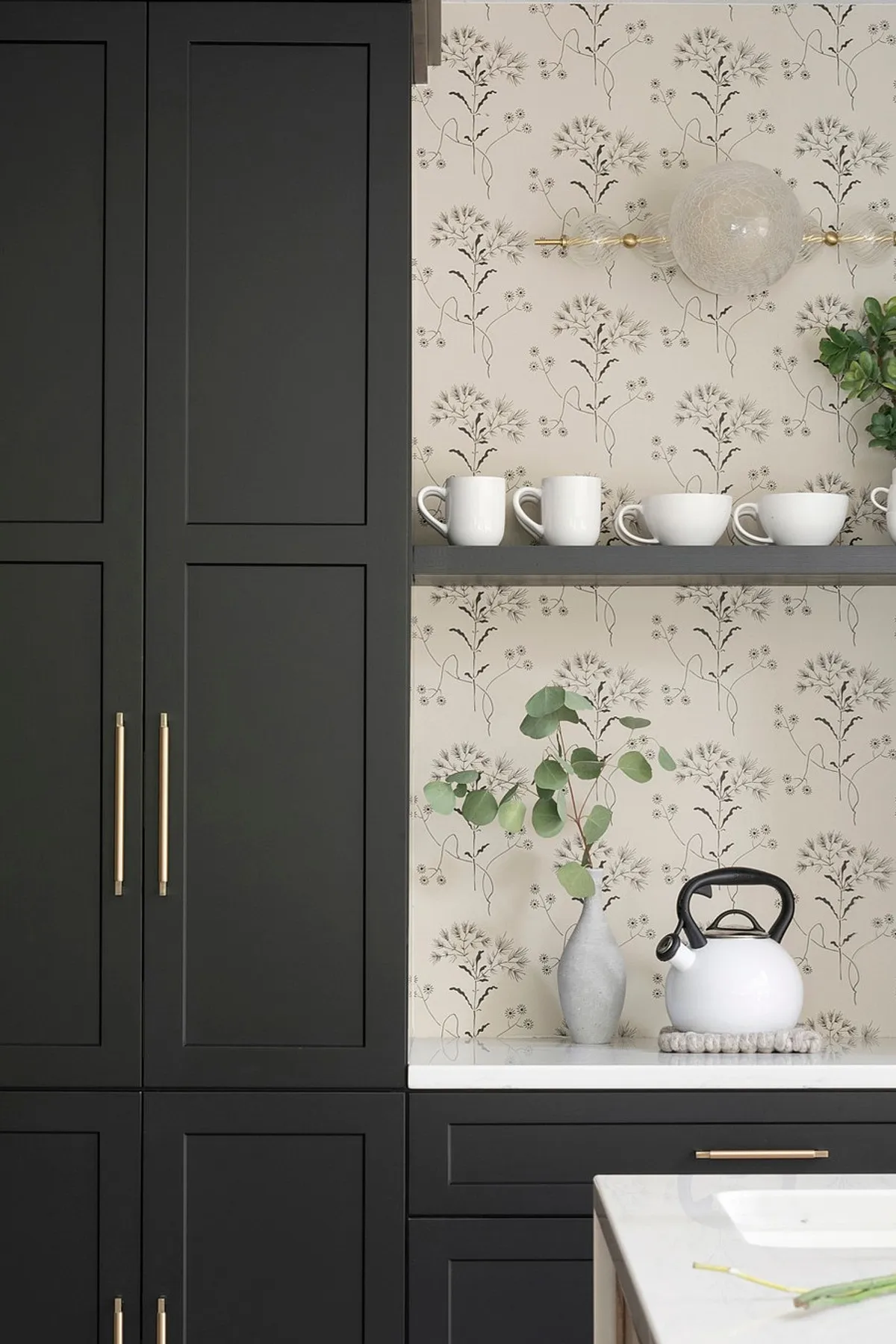 Modern dining room featuring black built-in cabinets, floral wallpaper, functional shelves, and decorative white mugs.