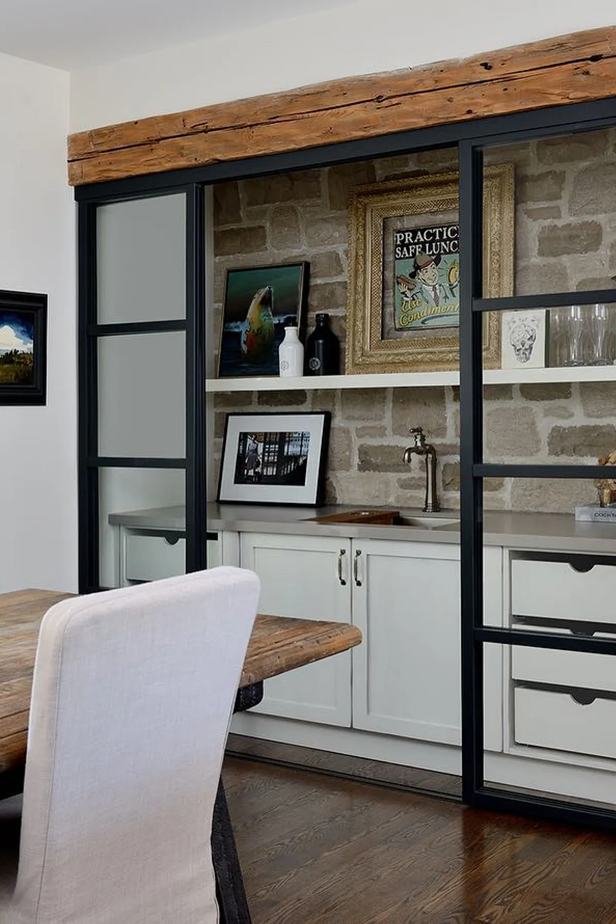 Modern dining room showcasing built-in cabinets, exposed brick wall, diverse artwork, and stylish storage solutions.