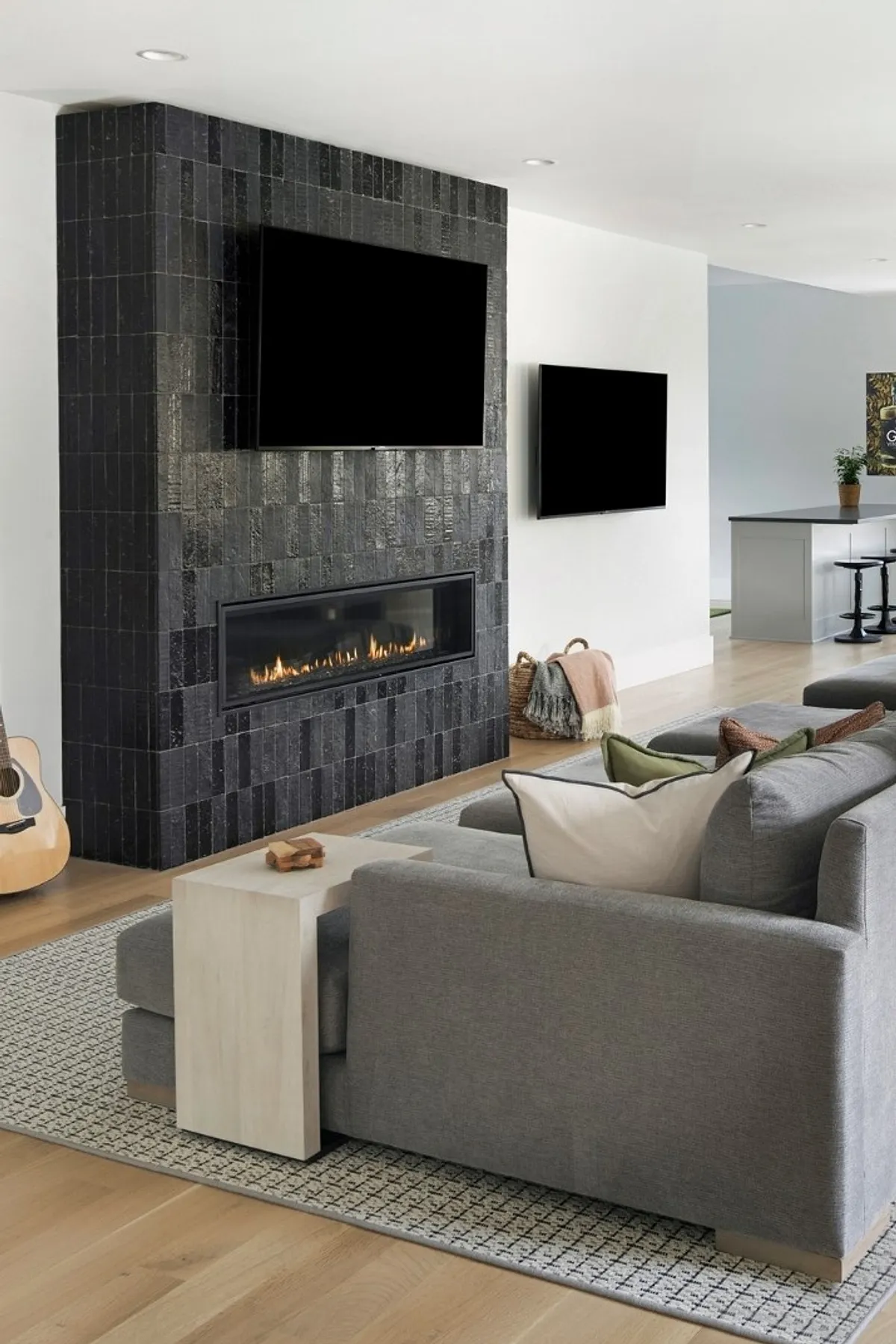 Stylish living room featuring a black stone TV wall with fireplace, cozy gray sofa, and decorative accents.