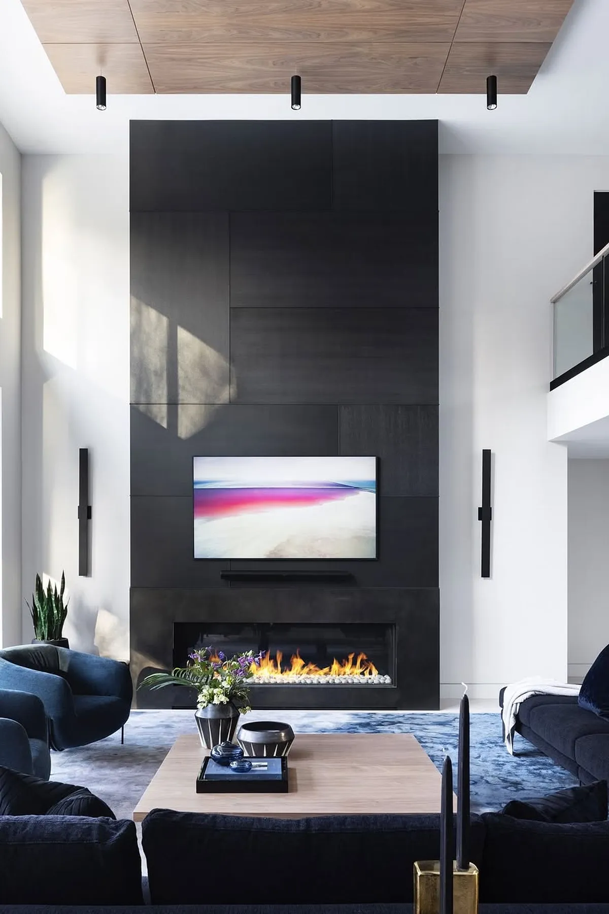 Modern living room with sleek black paneling TV wall, cozy fireplace, stylish furniture, and contemporary decor.