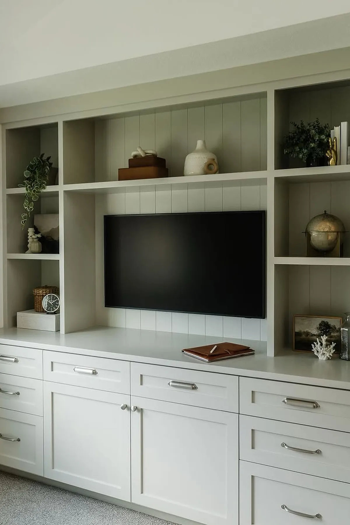 Modern white TV wall featuring custom storage solutions, decorative shelves, and minimalist cabinetry in living room.