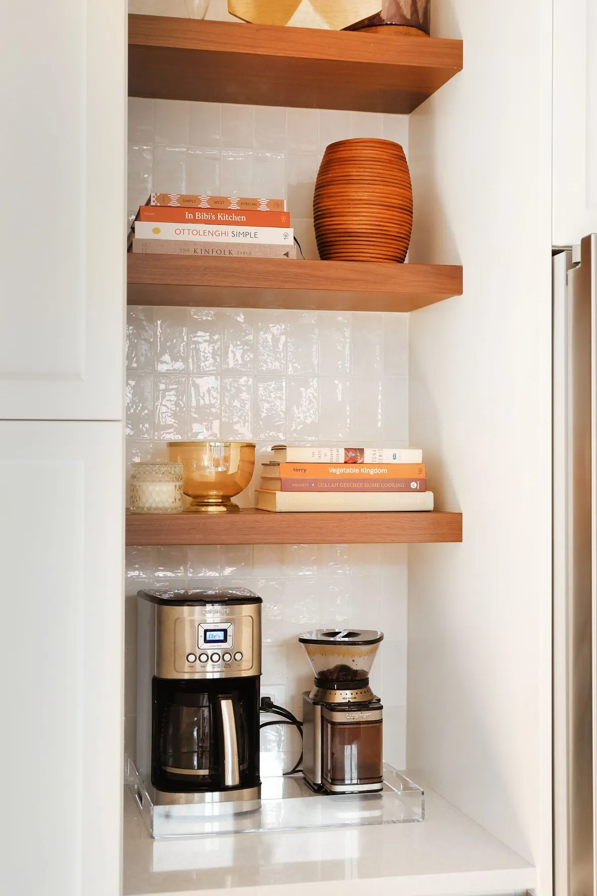 Coffee station with wooden shelves displaying books and decorative items above a coffee machine.