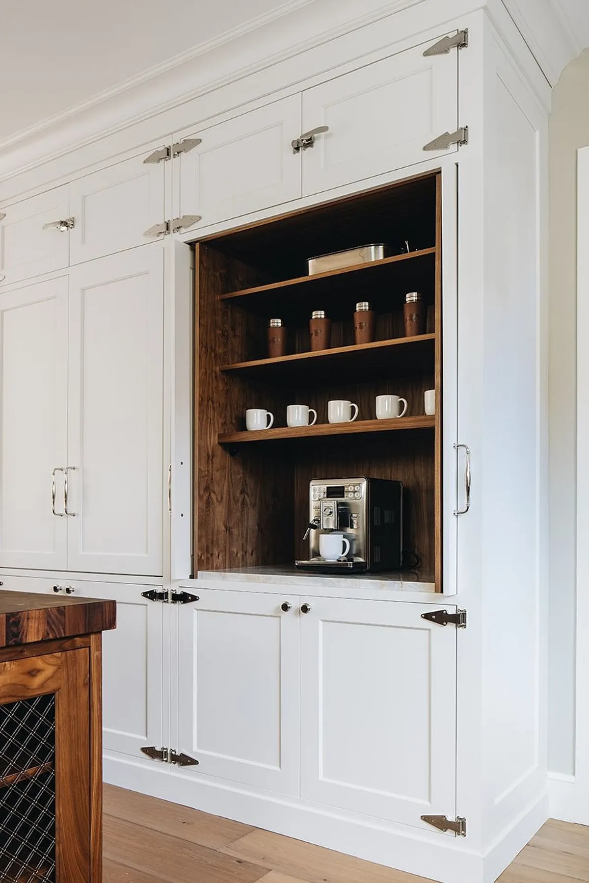White kitchen cabinetry with an open section revealing wooden shelves and a coffee machine.