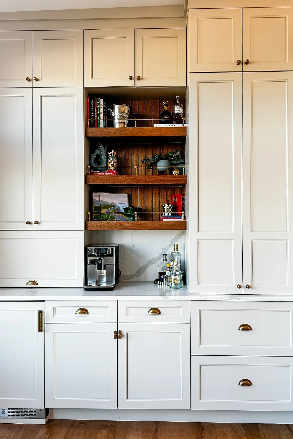 Built-in kitchen coffee station with wooden shelves, white cabinets, and an espresso machine on the counter.