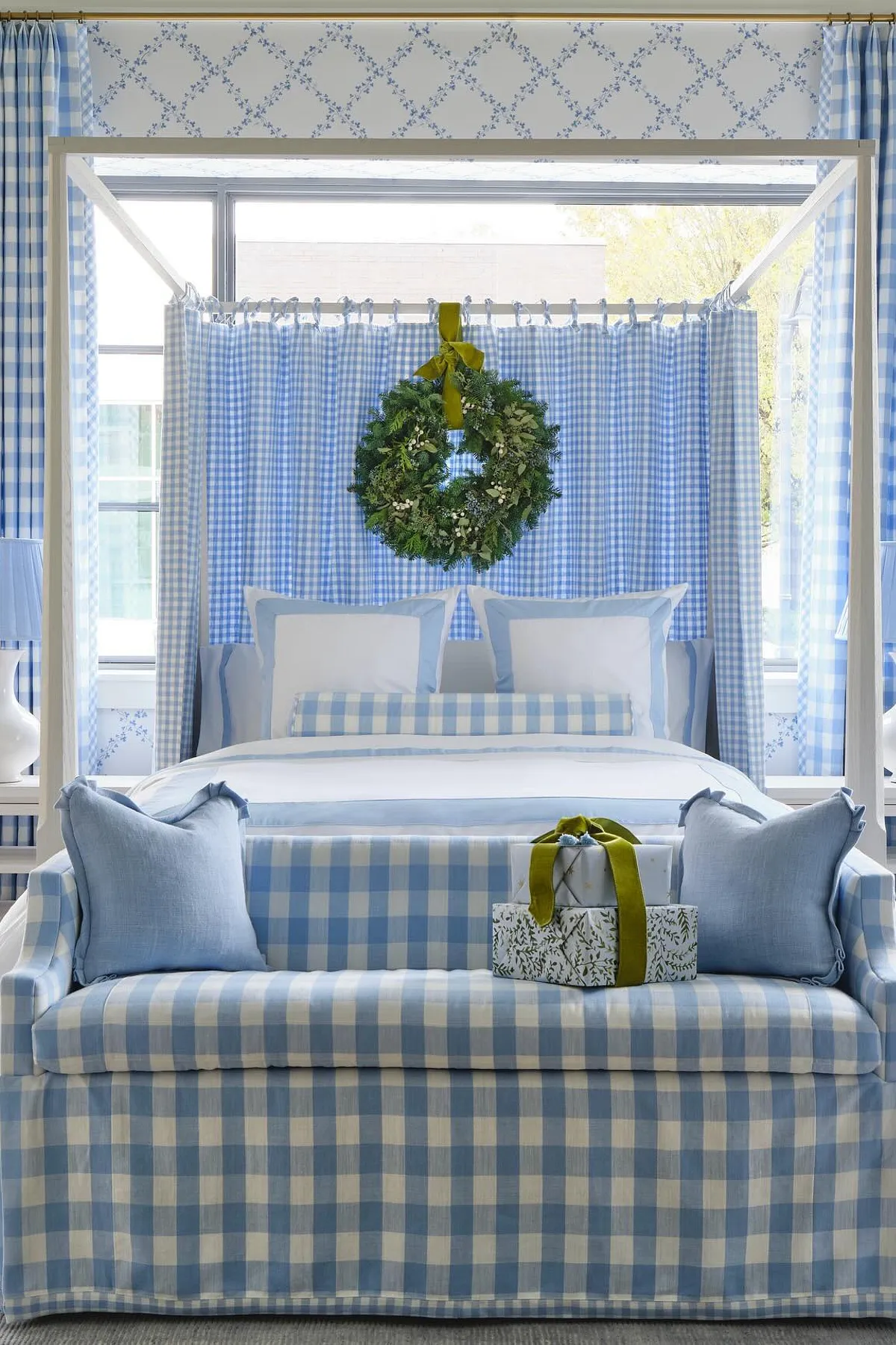 Bedroom featuring blue and white checked canopy, sofa, pillows, wreath above bed, and light-filled window.