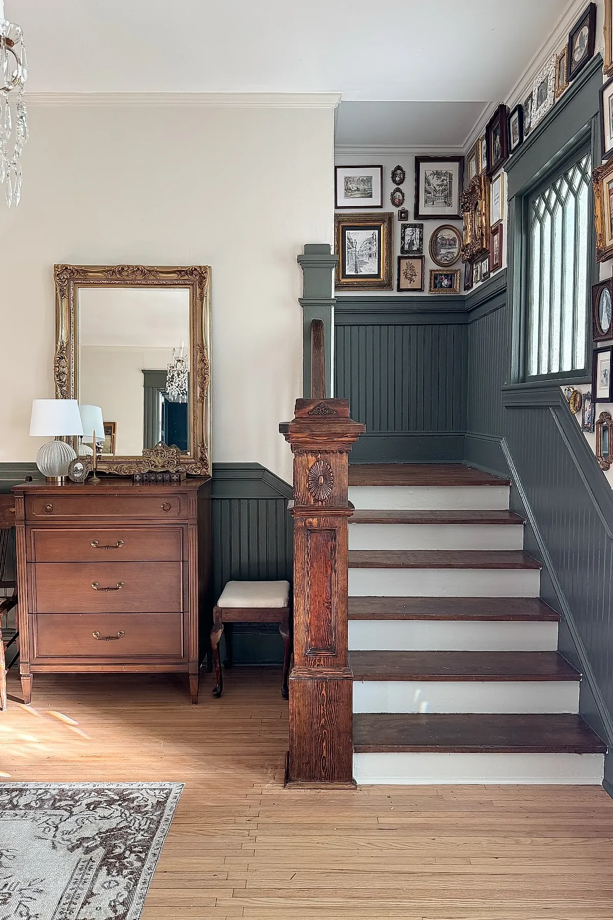 Staircase with ornate picture frames creating a vintage gallery wall effect, complemented by rich wood paneling.