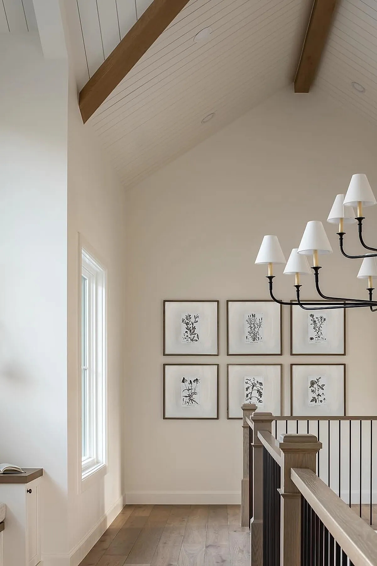 Staircase with a gallery wall featuring framed botanical sketches in minimalist wooden frames and a vaulted ceiling.