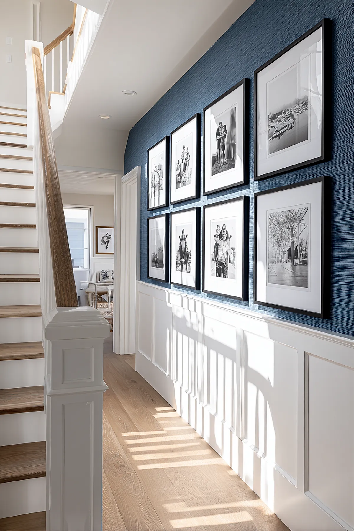 Staircase with a gallery wall featuring black and white photos in black frames against a blue textured wall.