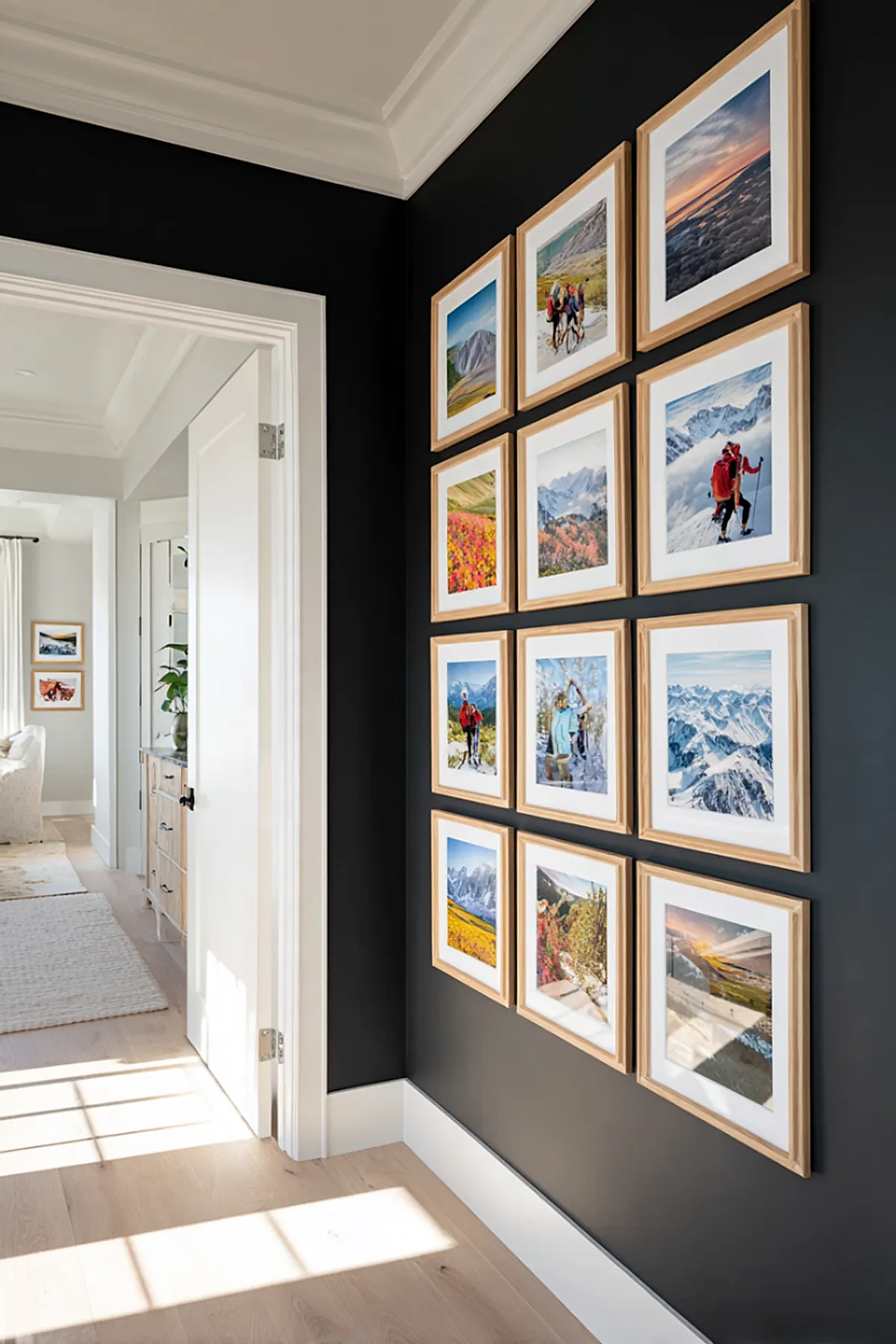 Hallway with a modern gallery wall featuring travel photographs in wooden frames on a dark wall.