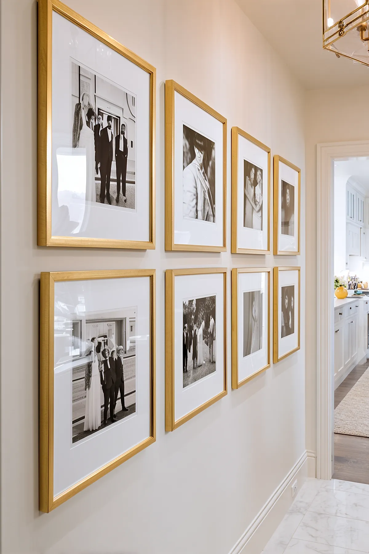 Hallway with a gallery wall featuring black and white photos in gold frames, arranged neatly on a light-colored wall.