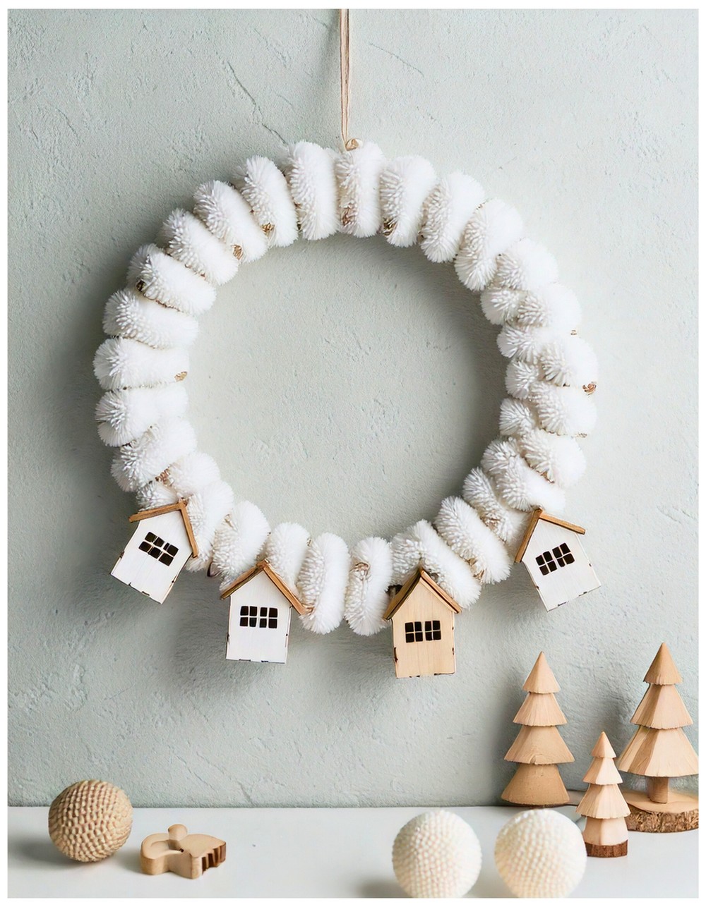Minimalist white wreath with pom-poms and tiny wooden houses