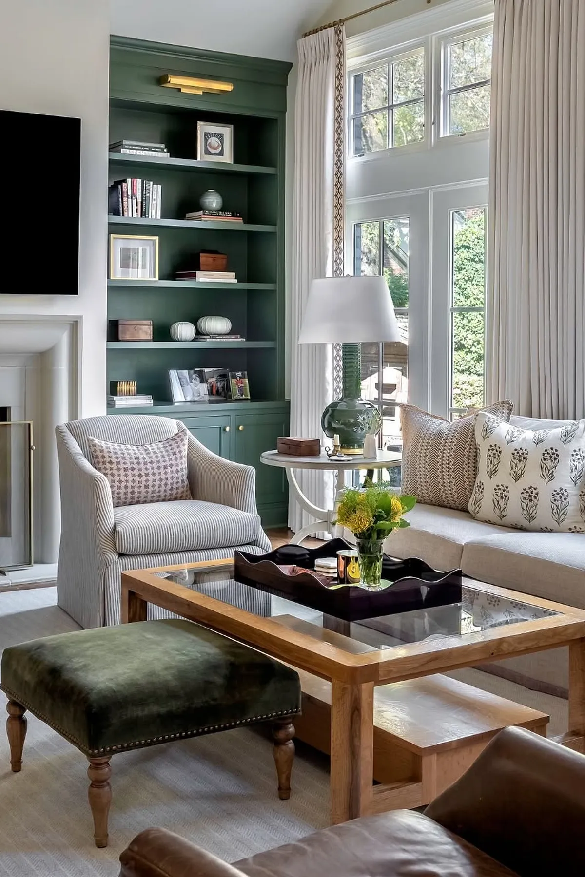 Elegant living room with green shelves, neutral furniture, textured pillows, and decorative objects.